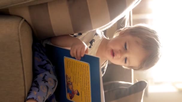 Küçük Bir Çocuk Bir Kanepede Otururken Görülüyor Tamamen Kitap Okumaya — Stok video