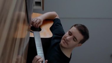 Adam gitar çalmayı ve modern dizüstü bilgisayardan online ders izleyerek şarkı söylemeyi öğreniyor. Erkek öğrenci evde yavaş çekimde uzaktan müzik eğitimi alıyor..