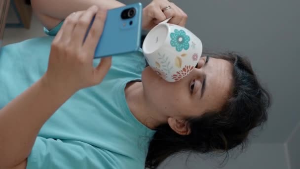Γυναίκα Απολαμβάνει Ζεστό Τσάι Ενώ Βλέποντας Βίντεο Στο Smartphone Μετά — Αρχείο Βίντεο