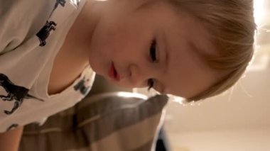 Küçük bir çocuk koltukta oturmuş, doldurulmuş bir hayvanla iletişim kurarken yaratıcı bir oyun oynar. Dikey görüntüler.