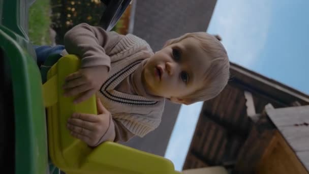 Cute Blond Maluch Próbuje Dostać Się Mały Ciągnik Zielonym Trawniku — Wideo stockowe