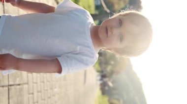 Küçük bir çocuk kaldırımda bir kadının yanında yürüyor, tipik bir arkadaşlık ve hareket sahnesi sergiliyor. Dikey görüntüler.