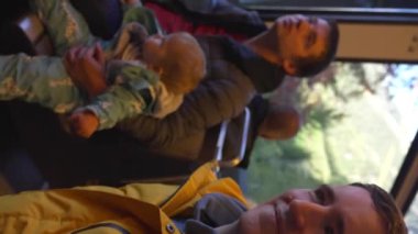 Trenle İsviçre 'ye yapılan eğlenceli seyahatin video kaydı. Küçük çocukları olan baba, erkek, kız ve arkadaşı oturulan tren vagonunun penceresinde dikey görüntülerde oturuyor..