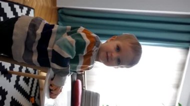 Kamera sola kaydediliyor. Masada oturan ve video oyunu oynayan sevimli çocuğa. Evdeki rahat oturma odasında dikey görüntüler var..