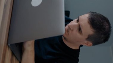 Konsantre erkek web tasarımcısı masadaki modern dizüstü bilgisayarda web sitesi geliştirir. Genç adam evdeki elektronik cihazla sıkı çalışıyor..