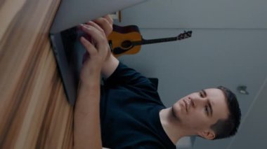 Odaklanmış programcı modern dizüstü bilgisayarda yeni bir video oyunu geliştirir. Apartman odasındaki ahşap masada oturan adam yavaş çekimde dikey çekim yapıyor..