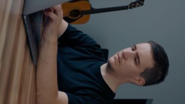 Odaklanmış erkek programcı evde dizüstü bilgisayarda yeni web sitesi geliştirir. Genç adam şık bir odada ahşap masada oturuyor ve yavaş çekimde çalışıyor..