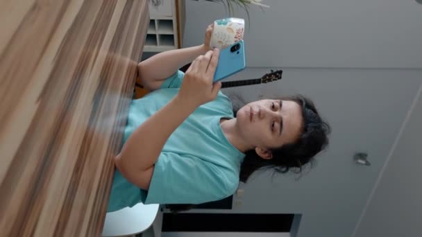 Νεαρή Γυναίκα Πίνει Τσάι Ελέγχοντας Κοινωνικά Δίκτυα Στο Smartphone Νυσταγμένη — Αρχείο Βίντεο