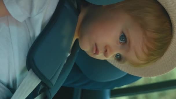 视频中 一个小男孩坐在车座上 戴着一顶帽子 垂直镜头 — 图库视频影像