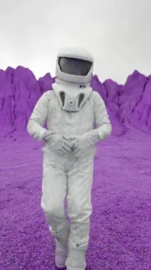 Neşeli bir astronot mor bir gezegende dans ediyor. Astronot uzak bir gezegene yaptığı yolculuktan çok memnun ve neşeyle dans ediyor. Dikey Çekim.