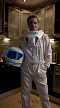 Astronot kostümü giymiş bir adamın portresi. Mutfaktaki bir NASA astronotu elinde kaskla kameraya bakıyor. Dikey Çekim.