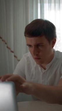 Freelancer 'ın acelesi var. Evde farklı bilgisayarlar üzerinde çalışıyor. Bir sürü işi tamamlamaya çalışıyor. Adam masadaki dizüstü bilgisayarı kapatıyor. Yakın plan dikey çekim..