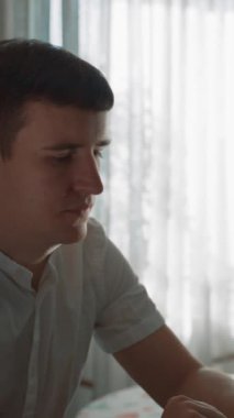 Yeni bir yazı için dizüstü bilgisayara bakan adamın POV 'u. Freelancer mutfakta oturur, pencerenin önünde kameraya döner ve yakın çekim dikey gülümser..