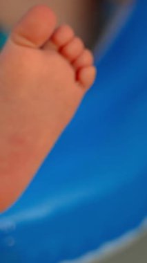 Lastik şişirilebilir bir oyuncağa yapışmış çocuk topuğunun yakın çekimi. Sahilde çocuklarla mutlu bir tatil yapma fikri.