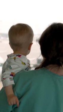 Bir anne ve çocuğu havaalanının penceresine yaklaşıyorlar. Genç bir anne kucağında bir bebekle ona uçağın dikey vuruşunu gösterir..