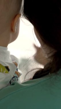 Anne, oğluna havaalanı terminalinin içinde uçak gösteriyor. Anne, yeni yürümeye başlayan çocuğa seyahate çıkmadan önce yeni kelimeler öğretiyor. Dikey Çekim.