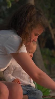 Bir anne çocuğuyla plajda güneşlenirken oynar. Maldivler 'de bir otel adasında tatilde bir aile olarak ayakta duran bir çocukla.