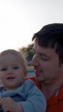 Baba, gün batımında orman dağları yakınlarında yürüyen sarışın bir çocuğu eğlendirir. Erkek ve tatlı çocuk yaz tatilinin tadını çıkarıyorlar. Yakın çekim yavaş çekim dikey çekim.