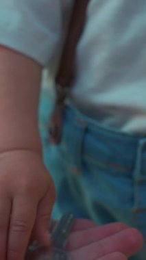 Anne, bahçedeki küçük oğluna lüks evin anahtarlarını verirken elini uzatıyor. Kadın ve çocuk hafta sonunu kırsalda yavaş çekimde, dikey çekimde geçiriyorlar..