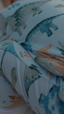 Tatlı sarışın çocuk alacakaranlıkta kumsalda ailesiyle eğlenirken eline kum alır. Bebek arabalı ve yeni yürümeye başlayan ebeveynler tatilden zevk alıyorlar. Yavaş çekim dikey çekim.