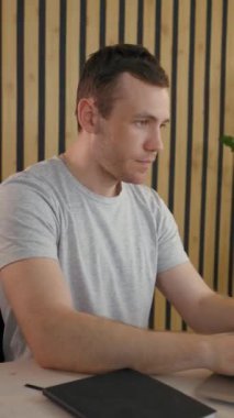 İşadamı, masa başında lambayı açarak proje için yeni fikirler düşünüyor. Genç adam modern ofiste dizüstü bilgisayarda çalışıyor. İç mimari tarzı, dikey çekimleri var..