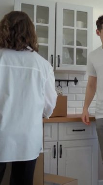 Kadın ve erkek tezgahın üstüne karton kutular koydular ve mutfaktaki cam masaya oturdular. Genç çift yeni daireye bir şeyler getirdikten sonra ara veriyor..