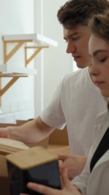 Mutlu çift mutfak aletlerini kağıt kutudan çıkarıp dolaplara koyuyor. Genç adam, yeni bir yere taşındıktan sonra eşyaların yerleştirilmesine yardım ediyor..