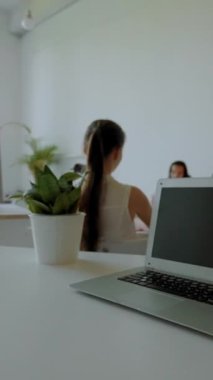 Genç bayan açık dizüstü bilgisayarın yanında oturan çalışma planını okuyor. İnsanlar yeni bilgiler edinir ve izleyiciler arasında profesyonel beceriler kazanır..