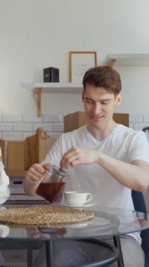 Koca, karısıyla mutfak masasında otururken fincanlara sıcak çay doldurur. Kurye taşınan genç çifte ağır karton kutular taşımada yardım ediyor..