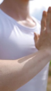 Genç kaslı adam Lotus 'ta meditasyon yapıyor. Yüksek çim tepesinde namaste' de el ele tutuşup poz veriyor. Sportif adam yeşil ağaçlara karşı mindere oturup yoga yapmayı seviyor..