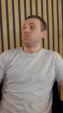 Çevrimiçi toplantıda, yakınlaştırma odasında video aracılığıyla iş arkadaşını dinleyen yorgun çalışanın POV 'si. Genç adam gözlerini ovuşturuyor modern ofis dikey çekimlerinde koltukta dönüp duruyor..