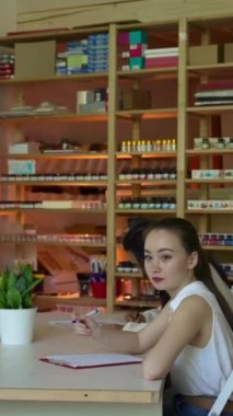 İş kadını, beyaz tahtaya karşı masalarda oturan çalışanların yanından geçiyor. Genç bayan öğretmenlik konferansını yönetiyor. Yavaş çekim dikey çekim..