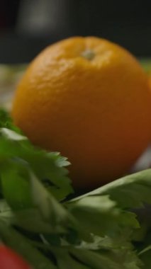 Yemek hazırlama sırasında mutfak masasında çeşitli meyve ve sebzelerin üzerinde hareket eden yakın çekim kamerası. Dikey çekim.
