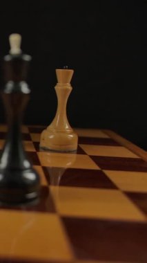Satranç oyuncusu şah mat beyaz vezirle siyah papazın. Kral Fell. Satrançta siyah figürler yenildi. Siyah arka planda tahta satranç taşları. Dikey çekim.