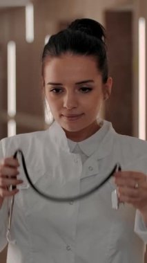 Hastanenin koridorunda boynuna steteskop takan güzel bir kadın cerrahın portresi. Gülümseyerek kameraya bakıyorsun. Tıp konseptinde refah ve cana yakın tutum