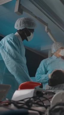 Kadın hastaların yanında duran ve hastanede çalışırken teşhis konan çok ırklı cerrahların etrafından dolaşın. Dikey çekim.