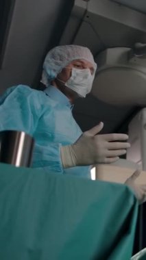 Bir erkek cerrah, kadın bir hastaya ameliyathanede lokal anestezi altında tavsiye veriyor. Dolly 'nin kamerası yavaş çekimde, aşağıdan görüntü. Dikey çekim.