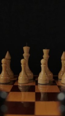 Dolly vurdu, satranç taşlarını fırlattı. Beyaz figürlerden siyah figürlere odaklanıyorum. Satranç oyununun başlangıcı. Dikey çekim.