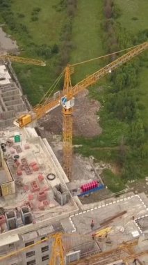 Vinç çekimleri, yeni modern bina inşaatçıları ve teknik aletler. Çok katlı bir dairenin yüksek yüksekliği. Dikey çekim.