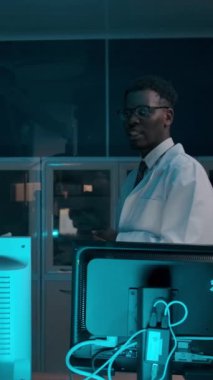 Esmer tenli ve Kafkas doktorları hasta tedavi planını tartışıyor. Ameliyathane camının arkasında profesyonel kıyafetli iki cerrah konuşuyor. Dikey çekim.