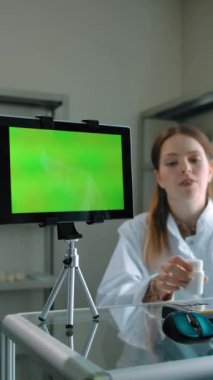 Müşteri eczaneden hap alıyor. Yeşil ekran kromakeyli tablet takip için hazır. Beyaz kadın kredi kartı ödemesi için terminali hazırlıyor. Dikey çekim.