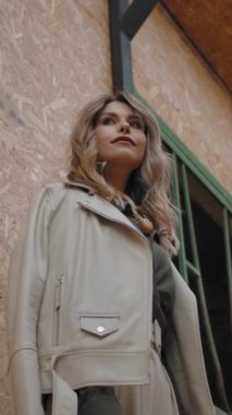 Tarlada ahır duvarının yanında durup düşünen modaya uygun bir kadın. Dikey çekim.