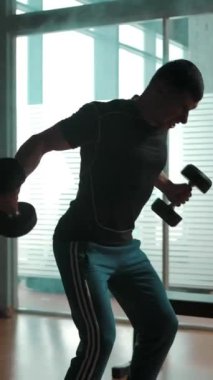 Elde çekilen beyaz kaslı erkek, halterleri dumanlı spor salonuna yayılmış halterlerle zar zor çalışıyor. Atış sporunun aksiyon tarzı. Dikey çekim.