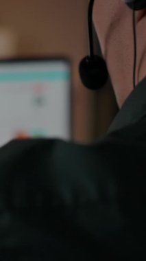 Çevrimiçi çağrı merkezi ev içinden çalışıyor. Dizüstü bilgisayarın arkasındaki adam. Müşteri desteklemek, mikrofon ve kulaklık kullanmak. Tanımlanamayan kişi. Dikey çekim.