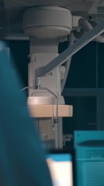 Ameliyathanede kadın bir hastanın yanındaki cerrah kontrol odasından bir meslektaşının önerisine olumlu yanıt veriyor. Dikey çekim.