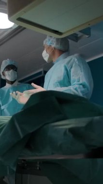 Düşük açı, üniformalı erkek tıp uzmanlarının iş konularını tartışırken modern laboratuarda tarayıcılı bir hastayla teşhis prosedürünü uygularken görüntülerini uzaklaştırır. Dikey çekim.