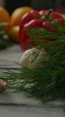 Yakın çekim makro kamera doğal sebzeler ve yeşil otlar üzerinden mutfaktaki sulu portakallara geçiyor. Vejetaryen yemeği veya öğle yemeği konsepti. Dikey çekim.