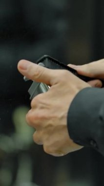 Kuaför, müşteri gelmeden önce ekipmanlarını temizler. Bir fırça ve budayıcı ile profesyonel bir berberin ellerine yakın çekim. Dikey çekim.