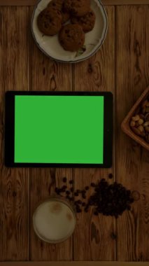 Modern tabletin krom anahtarlı üst görüntüsü nefis fındıklı kurabiyelerin yanına yerleştirilmiş ve sabahın ilk ışıklarıyla birlikte ahşap masaya bir fincan taze kahve. Dikey çekim.