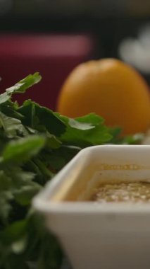 Kamera, çeşitli otlar ve sebzelerin yakınındaki masaya buharlı hazır şehriyelerle kutudan fırlıyor. Dikey çekim.